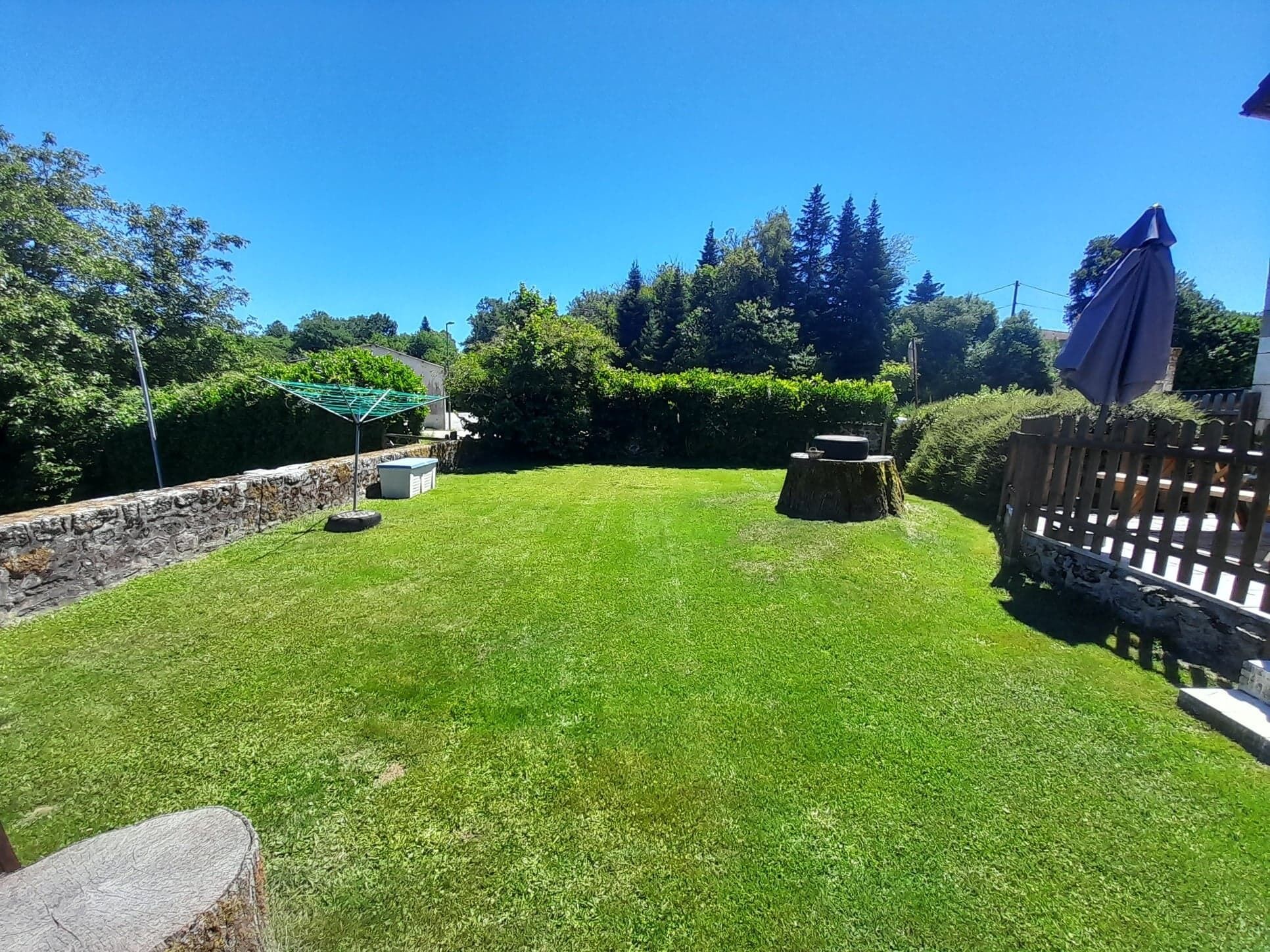 Un giardino curato con un muro in pietra, un pontile in legno e un prato.