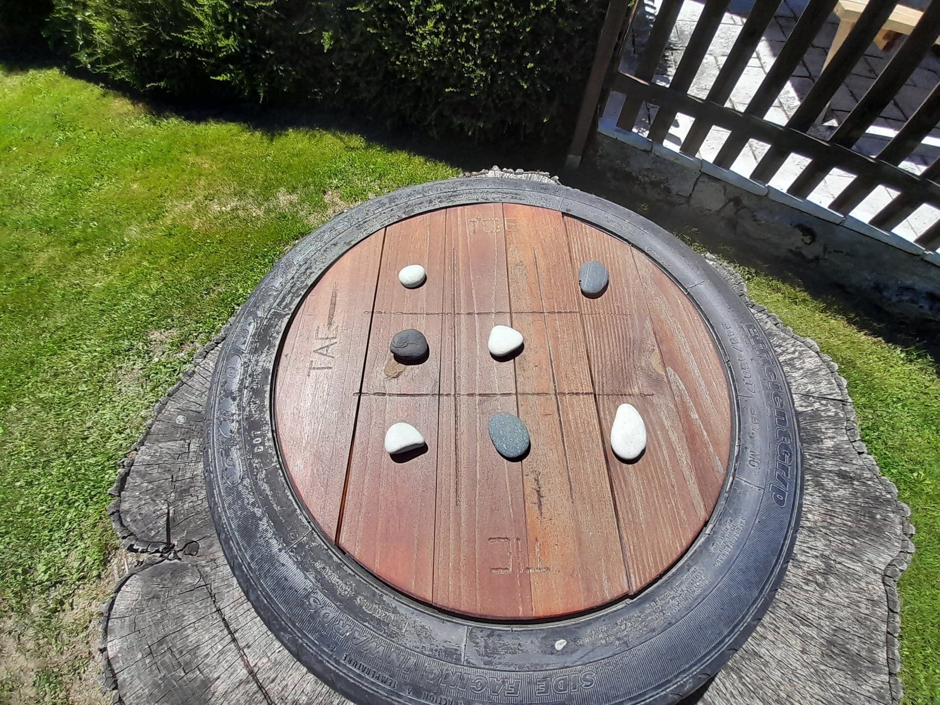 A tire-based fire pit with stones arranged on its surface.