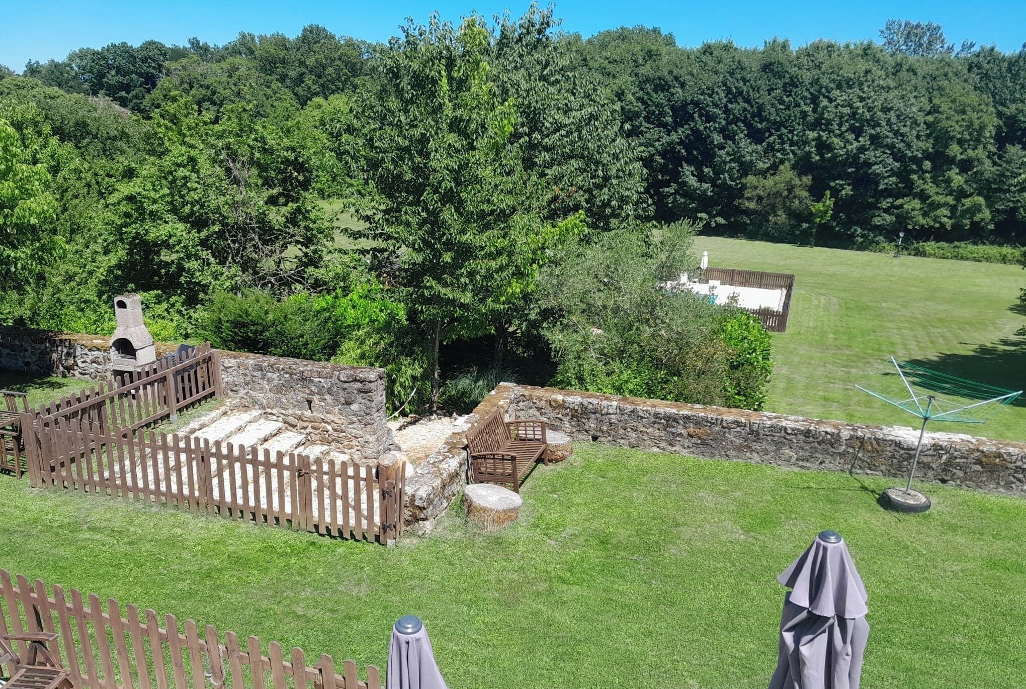 A rustic outdoor area with a stone structure, wooden fence, and seating.