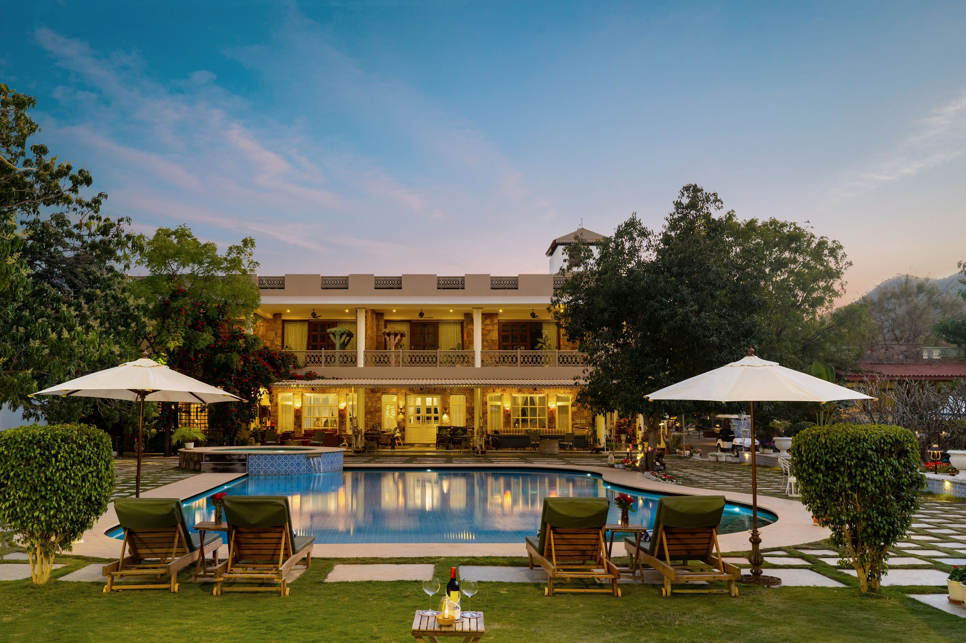 A large building with a pool, outdoor seating, and umbrellas.