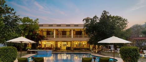 A large building with a pool, outdoor seating, and umbrellas.