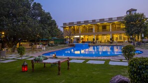 A hotel with a swimming pool, outdoor seating, and a well-lit courtyard. - Vatsalya Vihar - A Luxury Pool Villas Resort (Udaipur)