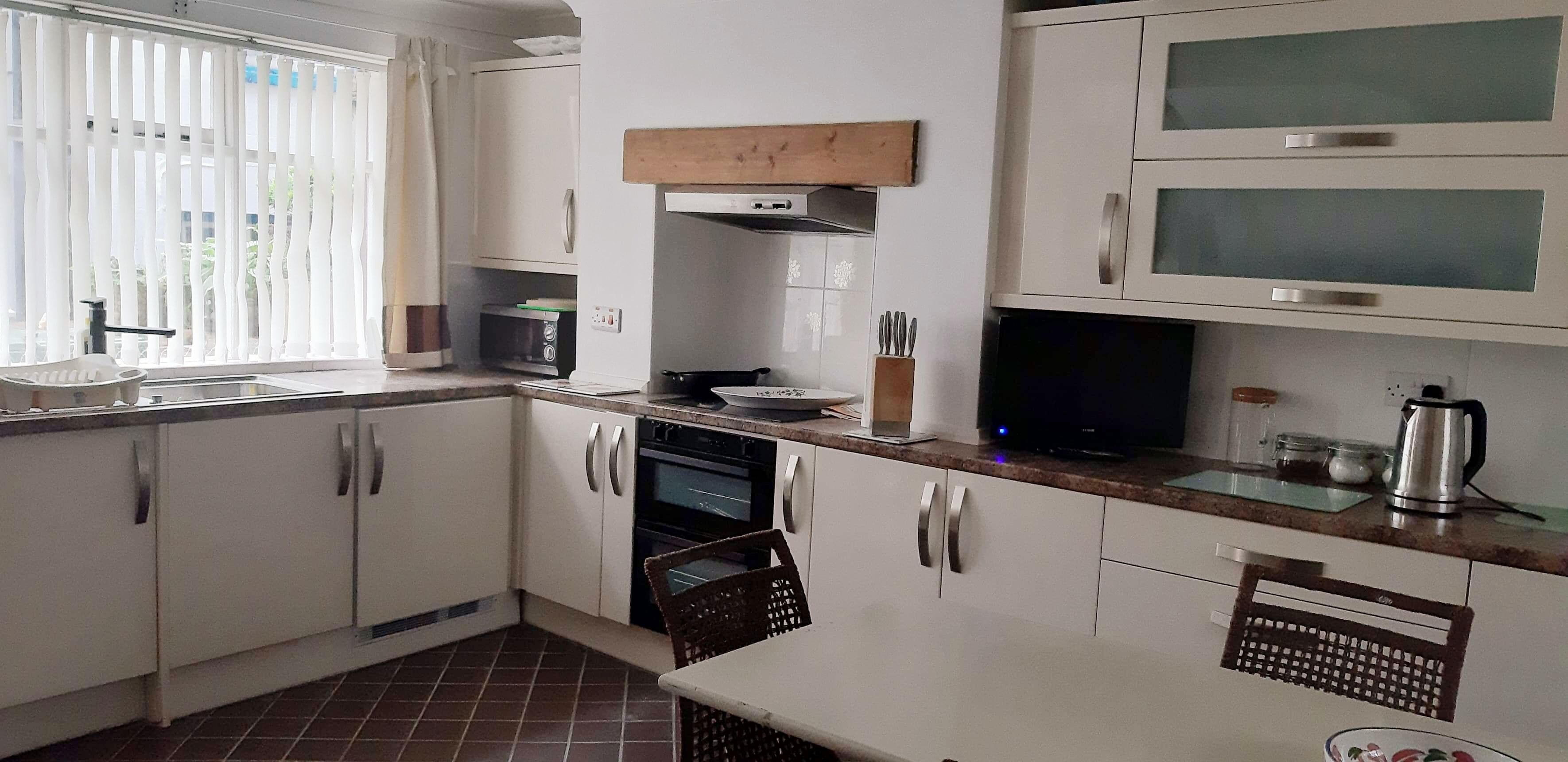 A kitchen with white cabinets, a microwave, a stove, and a coffee maker.