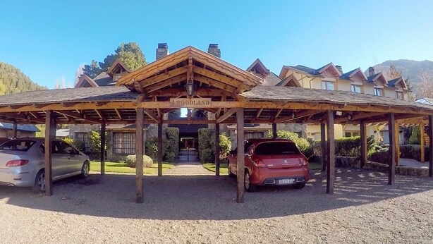 Een overdekte parkeerplaats met twee auto's, een houten constructie en een gebouw met de tekst 