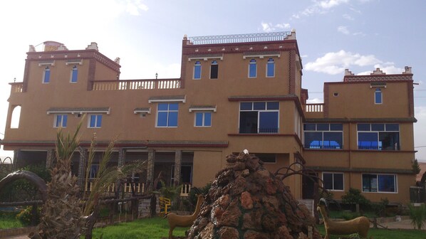 A multi-story building with a symmetrical facade, multiple windows, and a balcony on the upper floors.