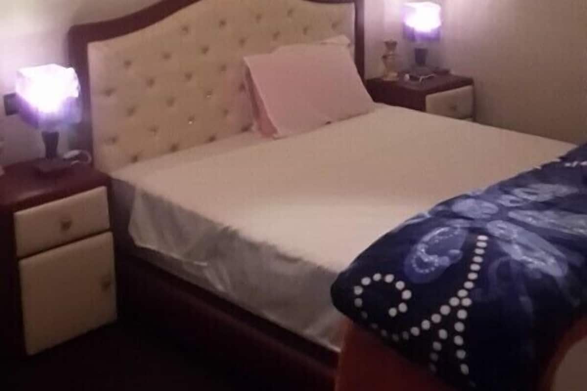 A bedroom with a bed, nightstands, and a lamp.