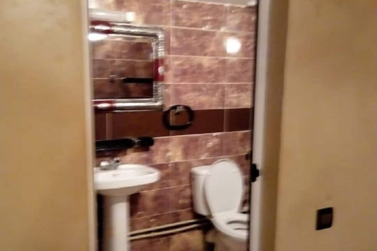 A bathroom with a toilet, sink, and mirror.