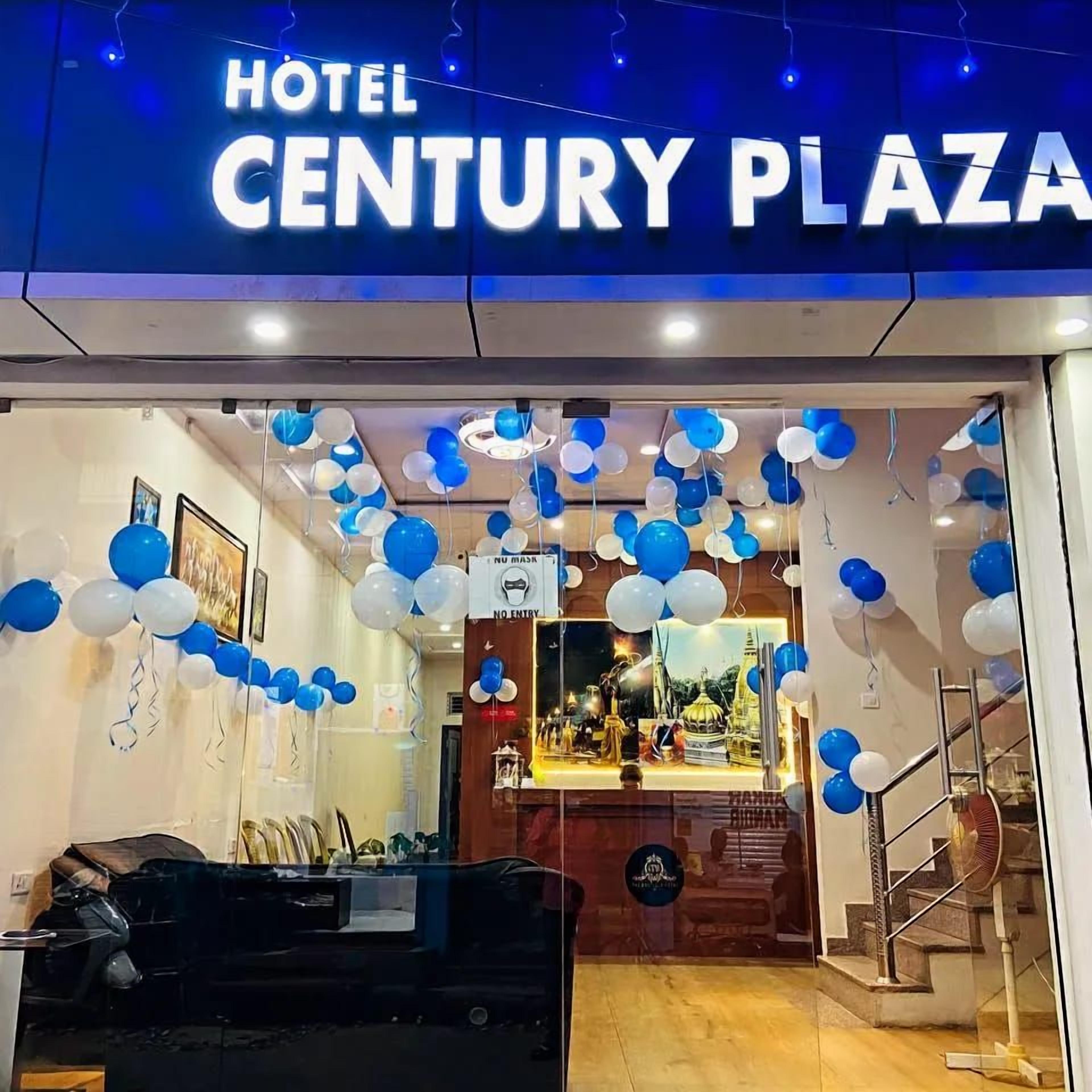 A hotel entrance with a sign reading 'HOTEL CENTURY PLAZA' and a festive decoration of blue and white balloons.