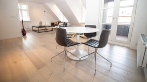 A spacious room with a round table and four chairs, a radiator, a window, and a door leading to an outdoor balcony. - City Point Reykjavik Center (Reykjavik)