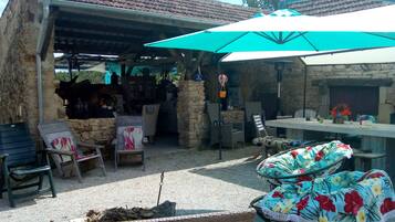 An outdoor patio area with stone walls, a table, chairs, and a large umbrella.
