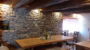 Ein rustikaler Essbereich mit Steinwand, Holztisch, Bänken und einer Laterne.