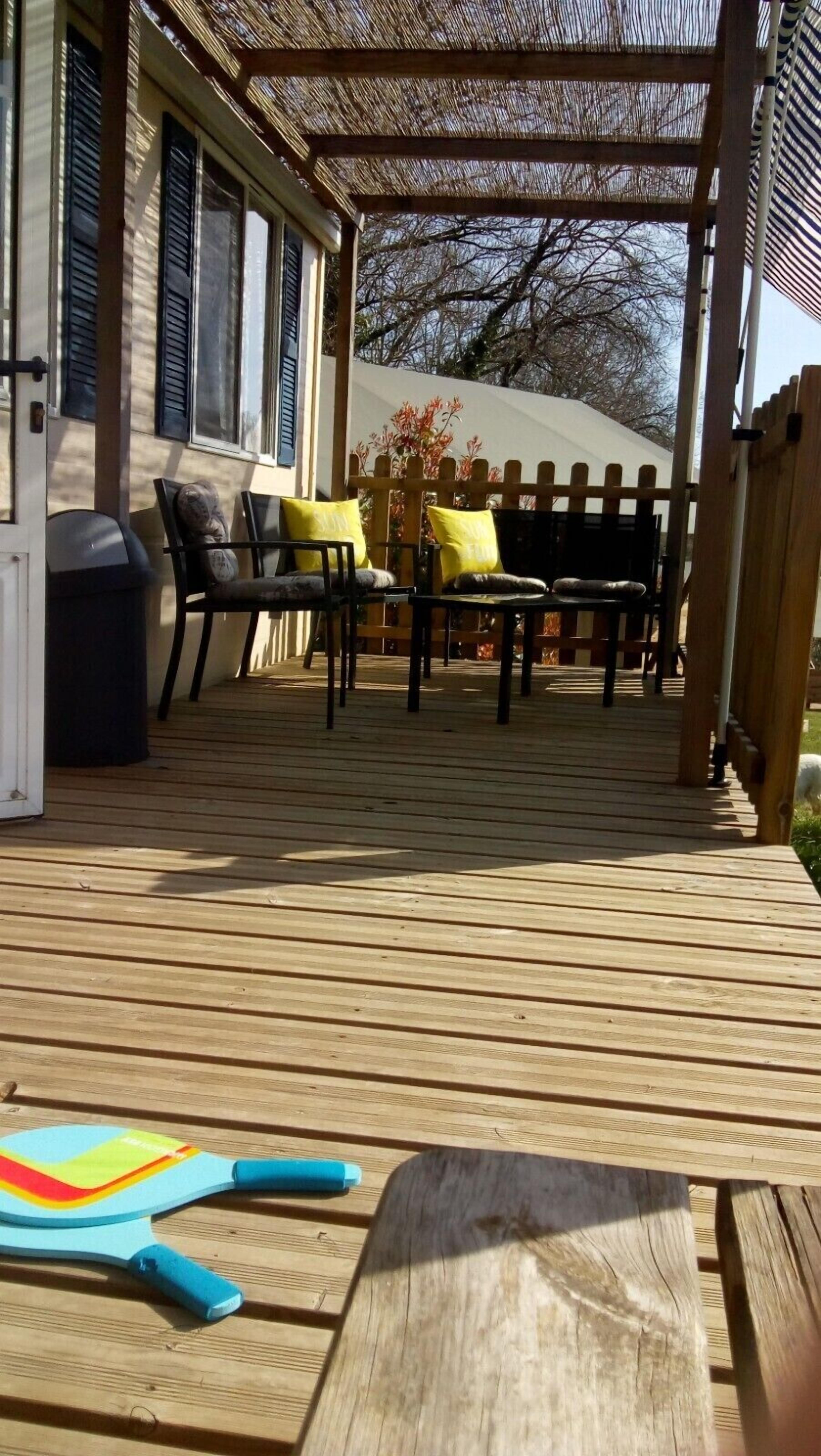 A wooden deck with outdoor furniture, including chairs and a table.