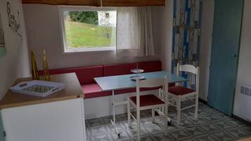 Una cocina compacta con un banco rojo, una mesa y una ventana con cortinas.