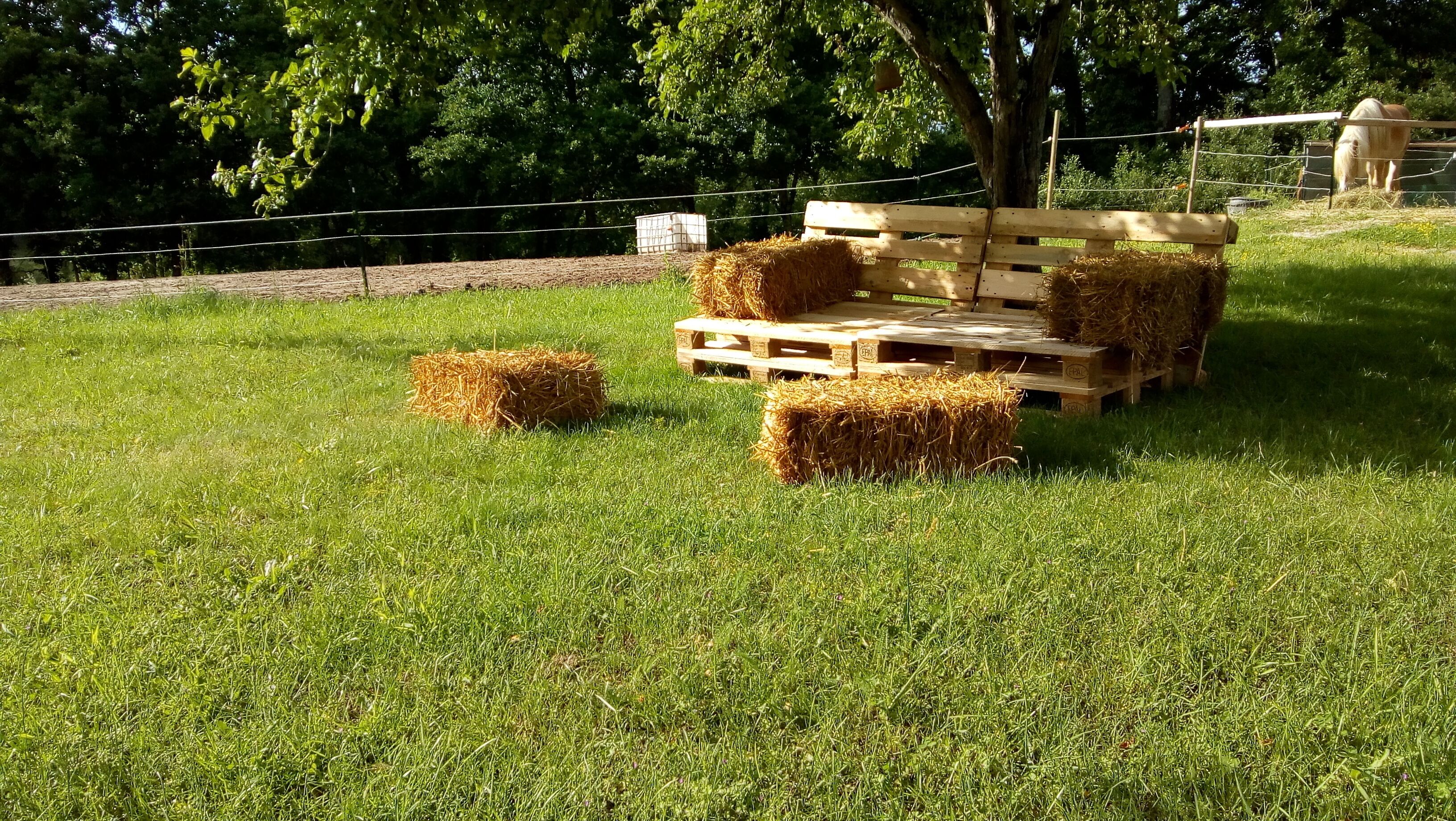 Een grasveld met hooibalen en een houten platformstructuur.