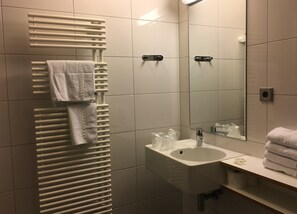 A bathroom with a white towel rack, a sink with a mirror, and a towel dispenser. - HOTELLERIE DU MONT STE-ODILE (Ottrott)