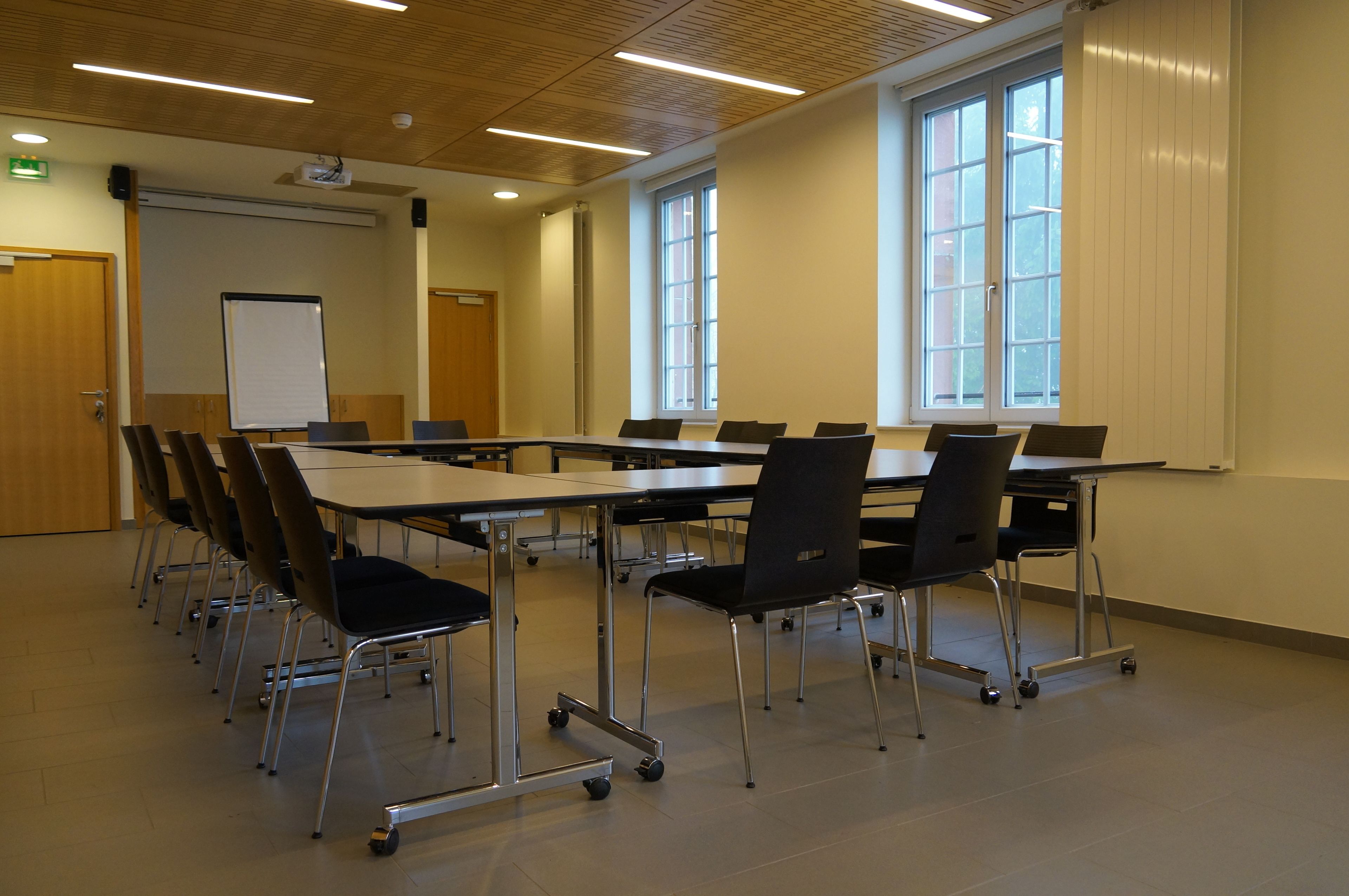 Un salón de conferencias con una gran mesa, sillas, una pizarra y un proyector.