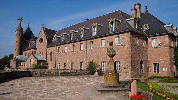 A historic building with a courtyard, stone walls, and a prominent tower. - HOTELLERIE DU MONT STE-ODILE (Ottrott)