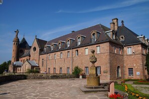 A historic building with a courtyard, stone walls, and a prominent tower. - HOTELLERIE DU MONT STE-ODILE (Ottrott)
