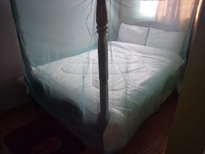 A bed with a mosquito net, a wooden headboard, and a white mattress. - The Plateau Breeze Hotel (Ruiru)