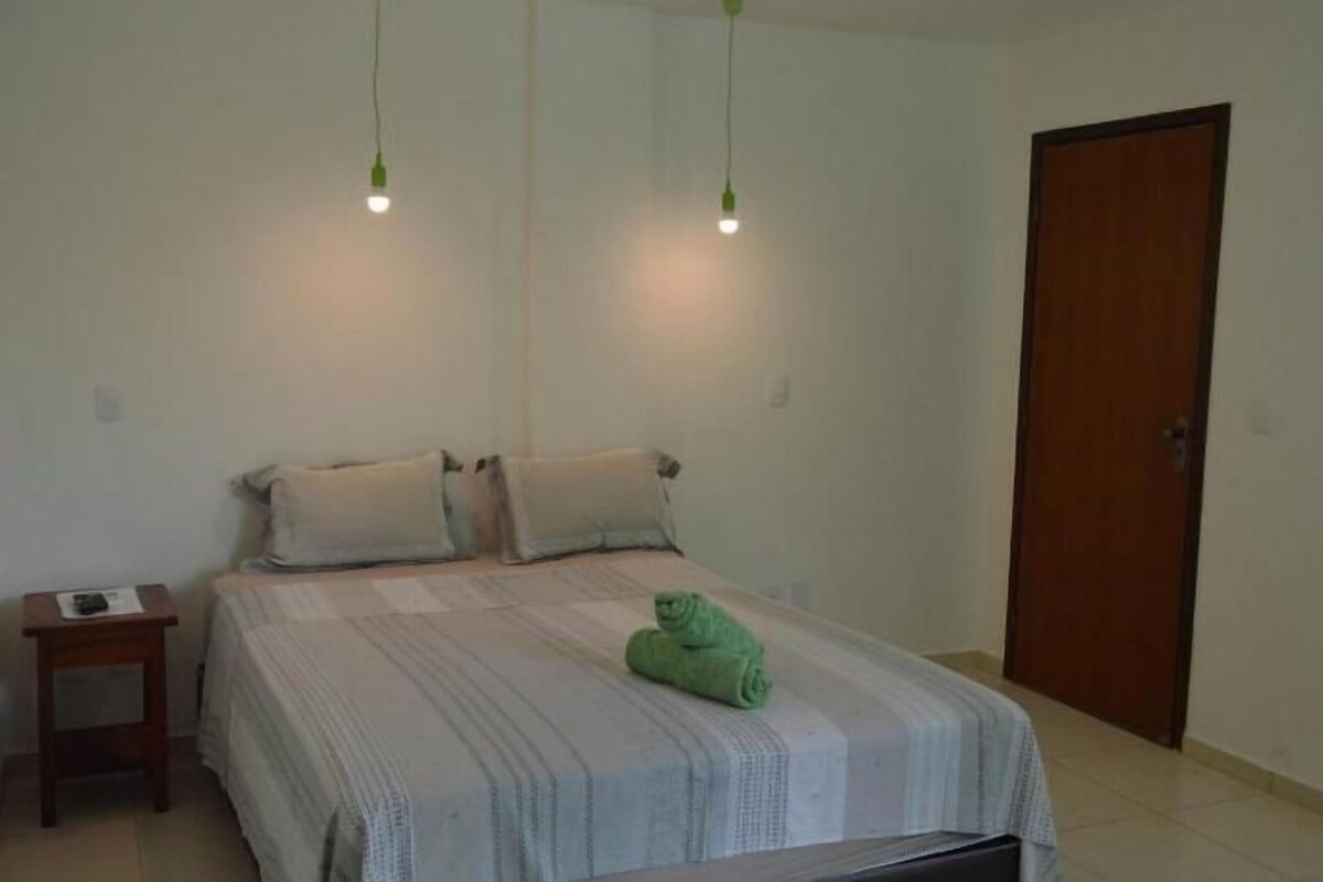A bedroom with a bed, bedside table, and a door.