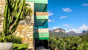 A modern building with a stone facade, large windows, and a view of mountains. - Pousada Vie (Palmeiras)