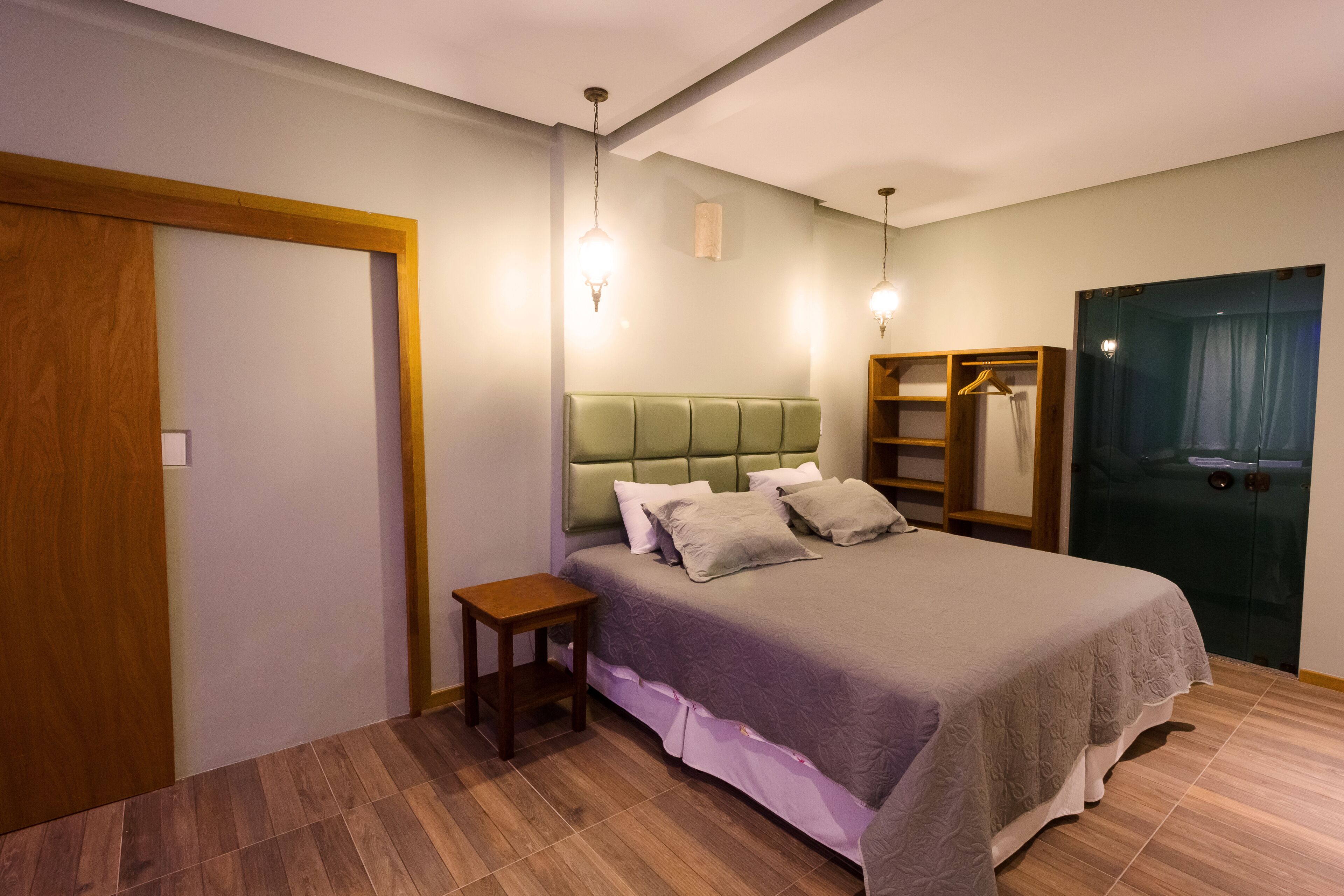 A bedroom with a bed, a bedside table, a wardrobe, and a mirror.