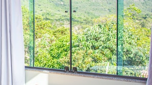 A room with a large window overlooking a mountainous landscape. - Pousada Vie (Palmeiras)