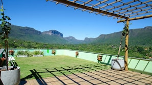 A rooftop terrace with a wooden pergola, potted plants, and a view of green mountains. - Pousada Vie (Palmeiras)