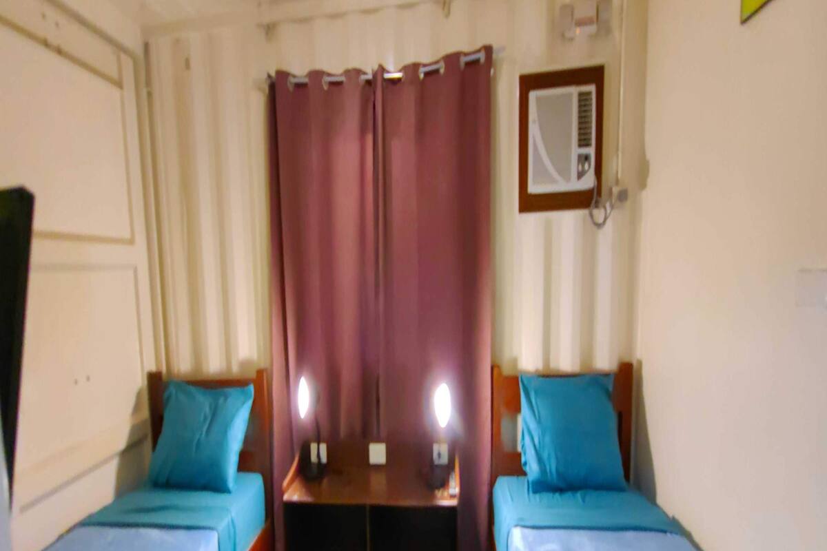 Una habitación con dos camas individuales, una mesa de madera y un espejo en la pared.