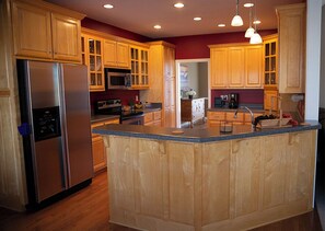 Enjoy cooking in this well-equipped kitchen with a central island, stainless steel appliances, and ample lighting.