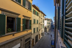 A narrow street with buildings on either side, featuring traditional architecture with shutters and balconies. - Borgo Pinti Angels (Florence)