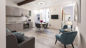 Une cuisine moderne avec des meubles gris, un coin repas avec une table et des chaises, et un salon avec un canapé et une lampe.