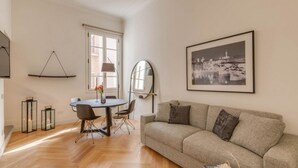 Una sala moderna con un sofá, una mesa de comedor y sillas. Se ve una ventana con vistas a un paisaje urbano.