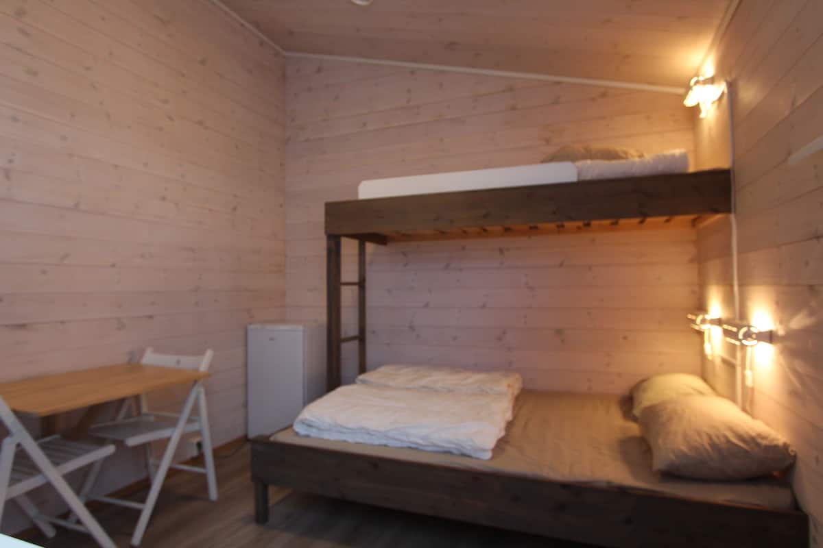 A bunk bed with a wooden frame and a desk with a chair beside it.