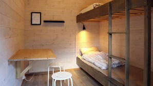 A small, wooden room with bunk beds, a desk, and two stools. - Trolltunga Camping (Ullensvang)