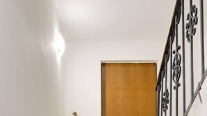 Una escalera con una puerta de madera en la parte superior, un felpudo en la base y una figura decorativa de Papá Noel sobre un tocón.
