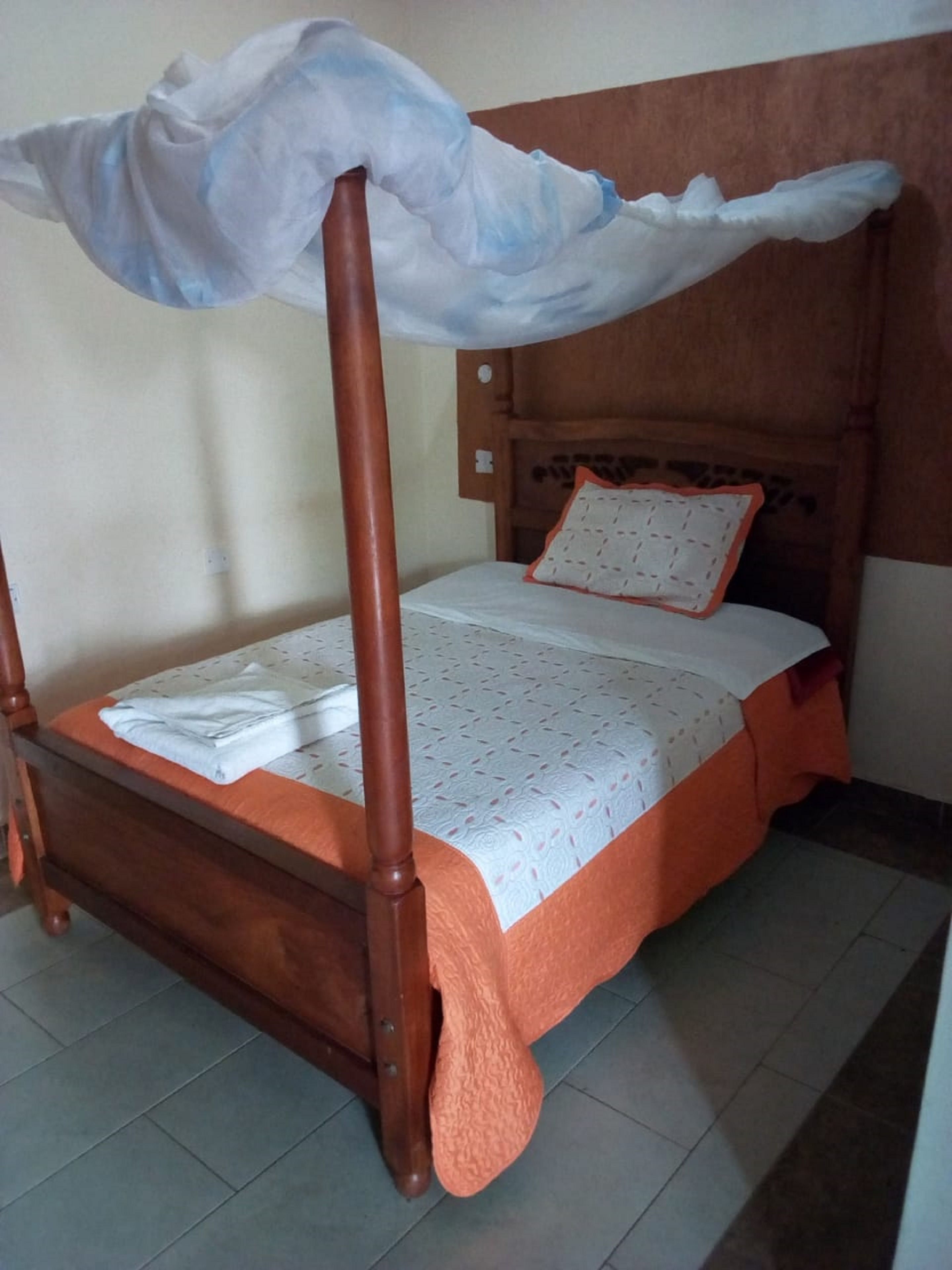 A single bed with a wooden frame and a mosquito net.
