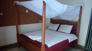 Un lit à baldaquin avec des poteaux aux quatre coins, une structure en bois et une couvre-lit rouge.
