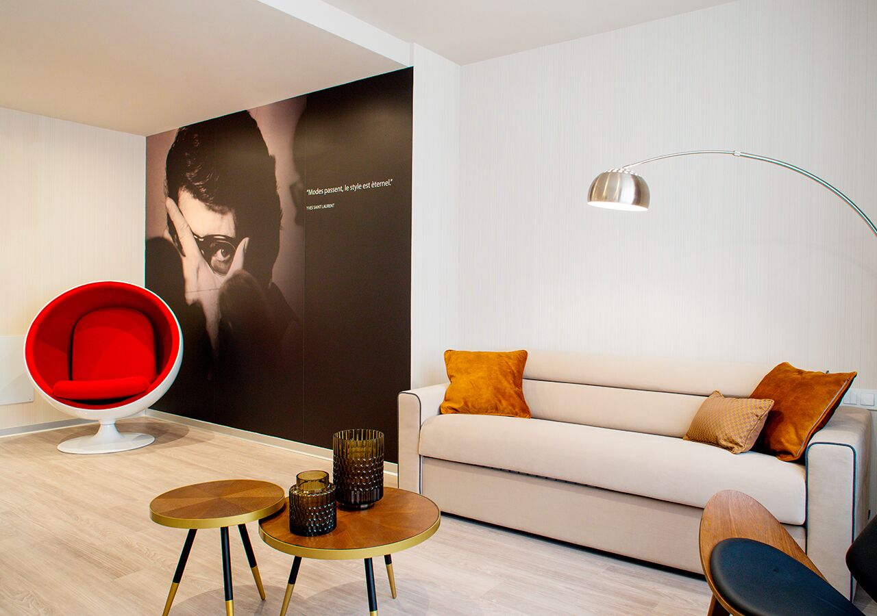 Ein modernes Wohnzimmer mit einem roten Sessel, einem weißen Sofa und einer Stehlampe.