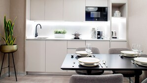 Une cuisine moderne avec des meubles blancs, un plan de travail noir et un coin repas avec une table dressée pour quatre personnes.