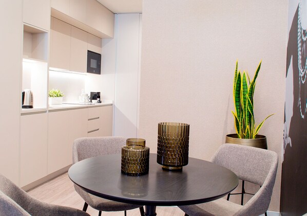 A modern dining area with a round table, two chairs, and two decorative glass vases.