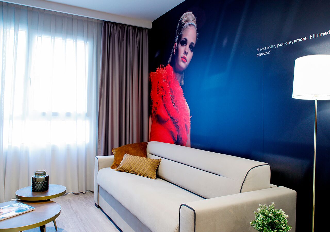 A modern living room with a beige sofa, a round coffee table, and a large poster on the wall.