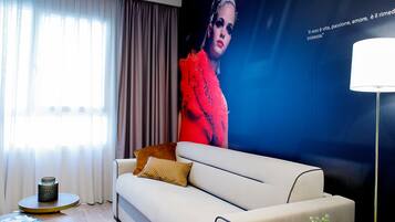A modern living room with a beige sofa, a round coffee table, and a large poster on the wall.