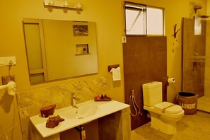 Ein Badezimmer mit Waschbecken, Toilette und Dusche. Über dem Waschbecken befindet sich ein Spiegel und ein Handtuch hängt an der Wand.