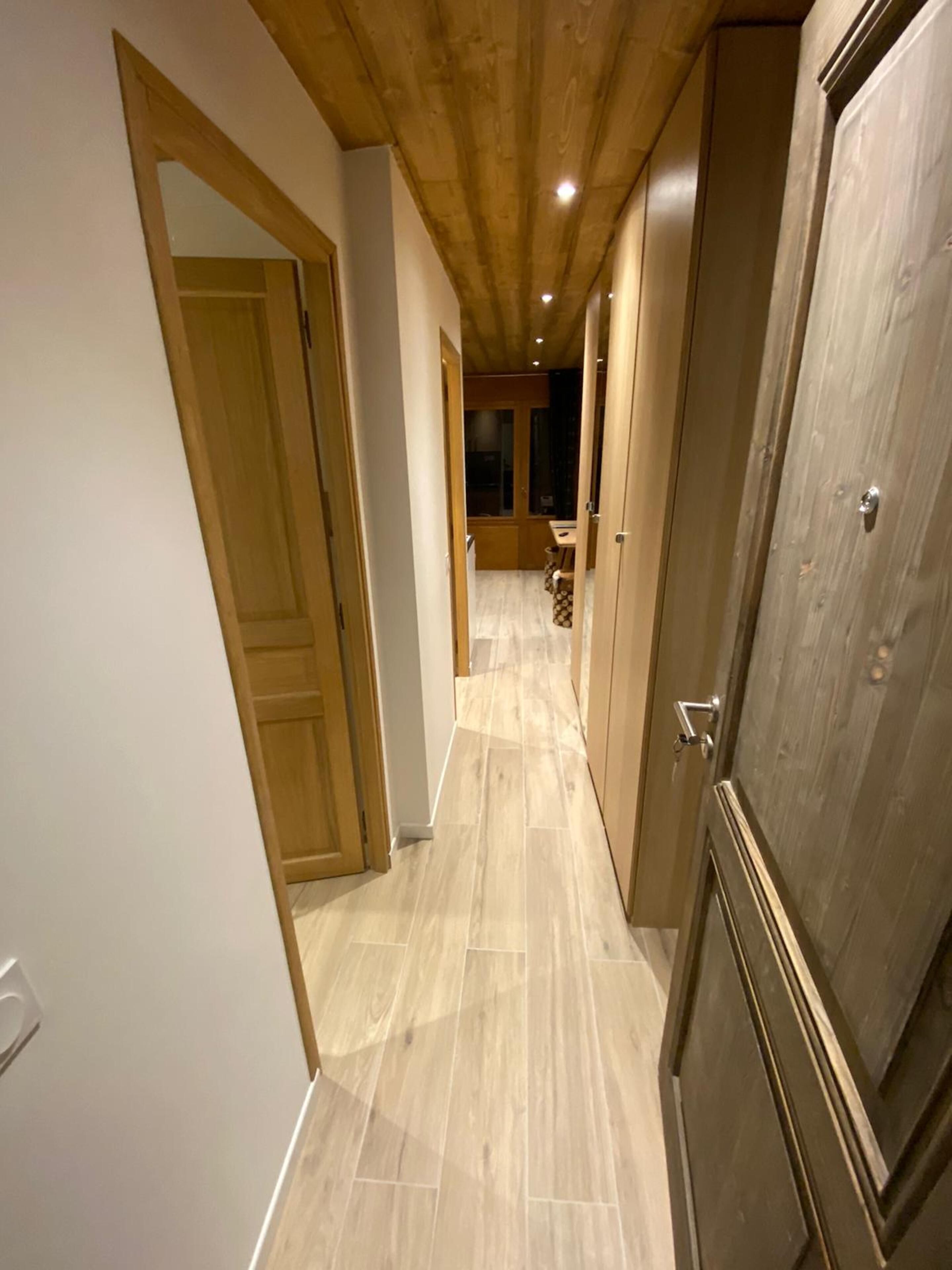 A narrow hallway with wooden doors and a tiled floor.