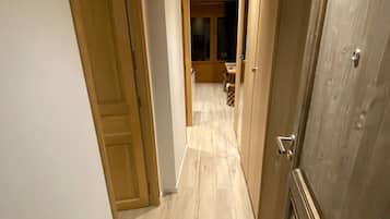 A narrow hallway with wooden doors and a tiled floor.