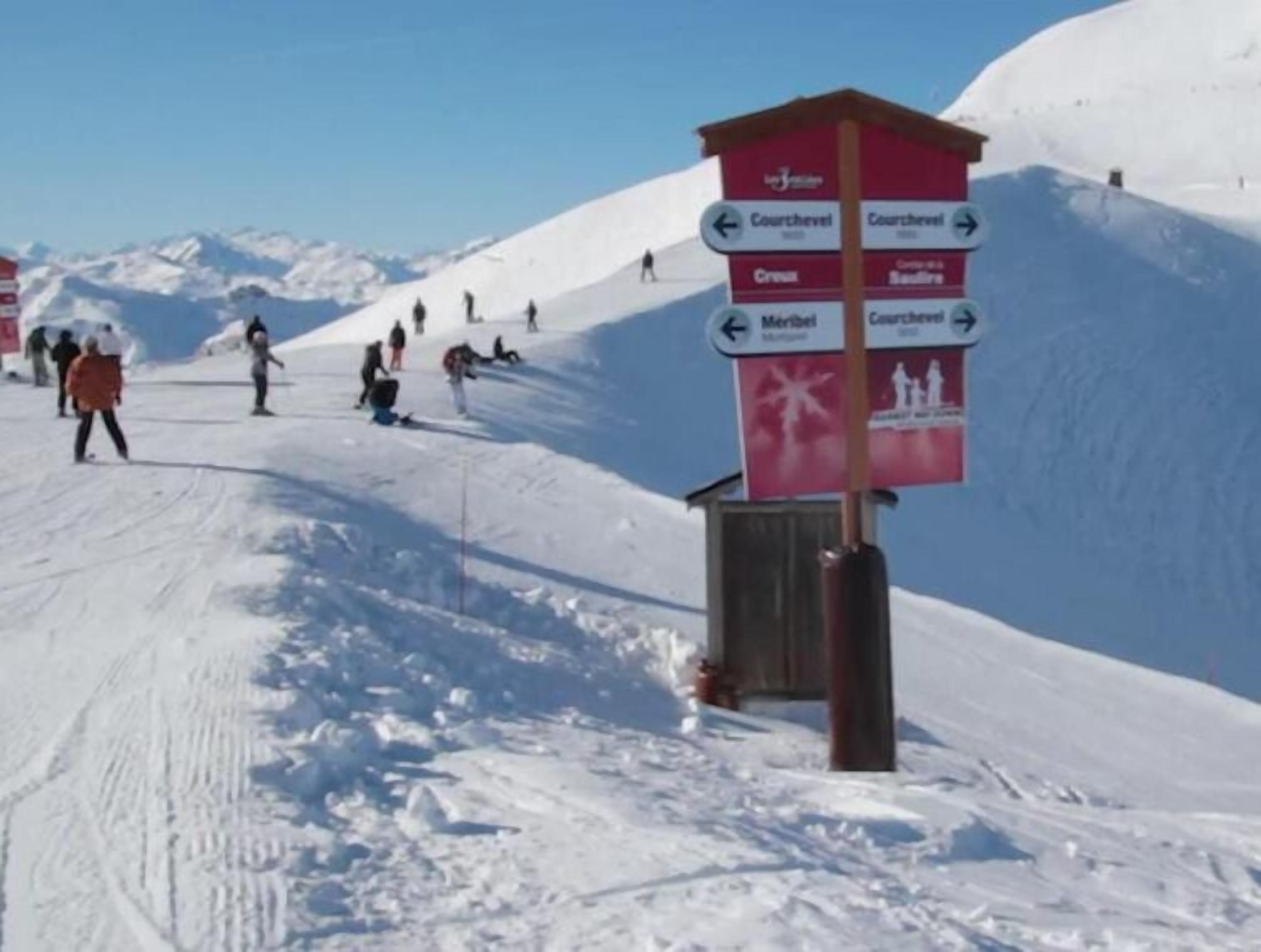 Pista da sci con un segnale che indica le direzioni per Courchevel, Meribel e altre località.