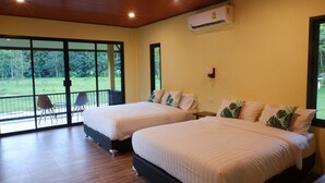Hotelkamer met twee bedden, een grote schuifglazen deur naar een balkon en een airconditioning op de muur.