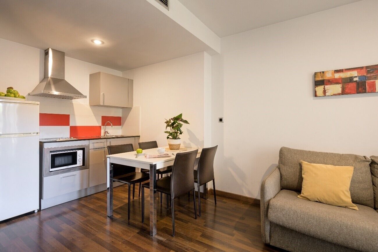 Una cocina compacta con comedor, un sofá y un cuadro en la pared.