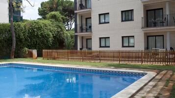 A rectangular swimming pool with a tiled edge, surrounded by a wooden deck and a low brick wall.